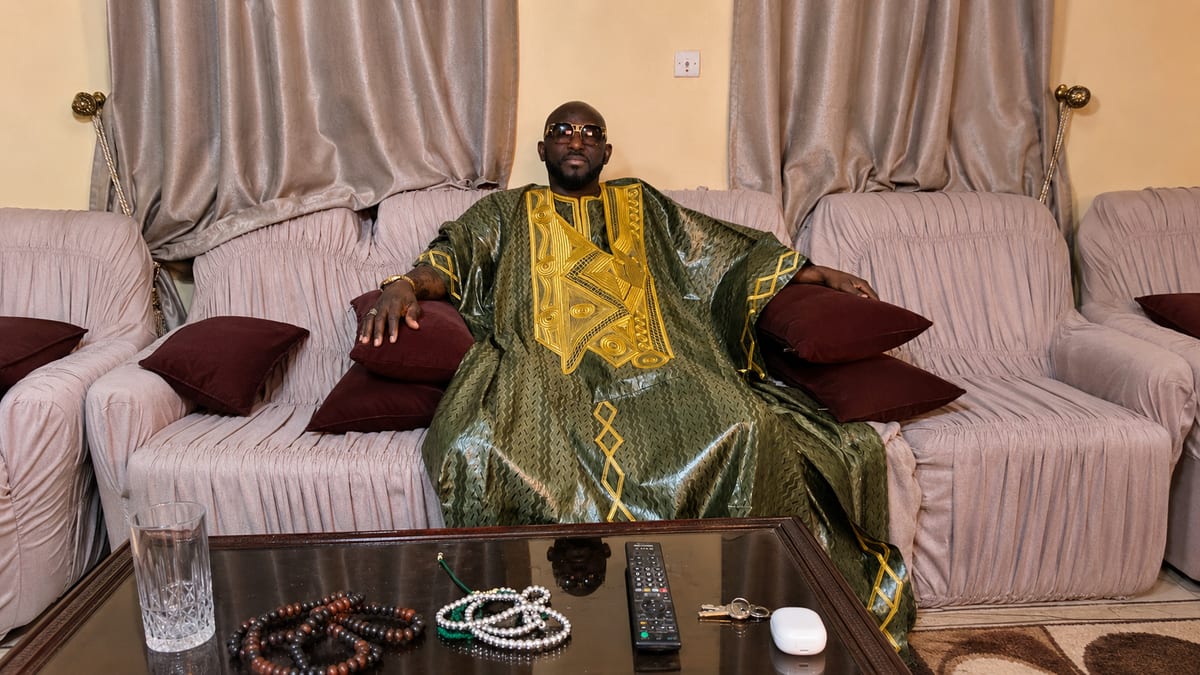 Marabout Djibril in a green and gold boubou, prayer beads laid before him
